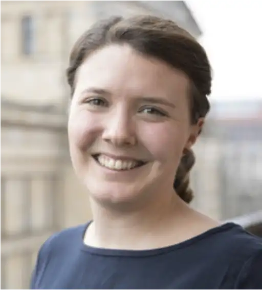 Das Bild zeigt ein Portrait von Kristina Herbst, die freundlich in die Kamera schaut und lächelt.